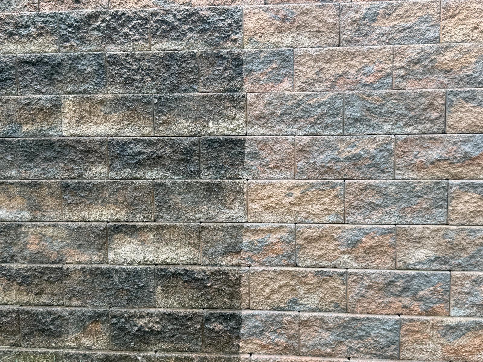 Close-up of a stone wall, half cleaned and half showing built-up grime